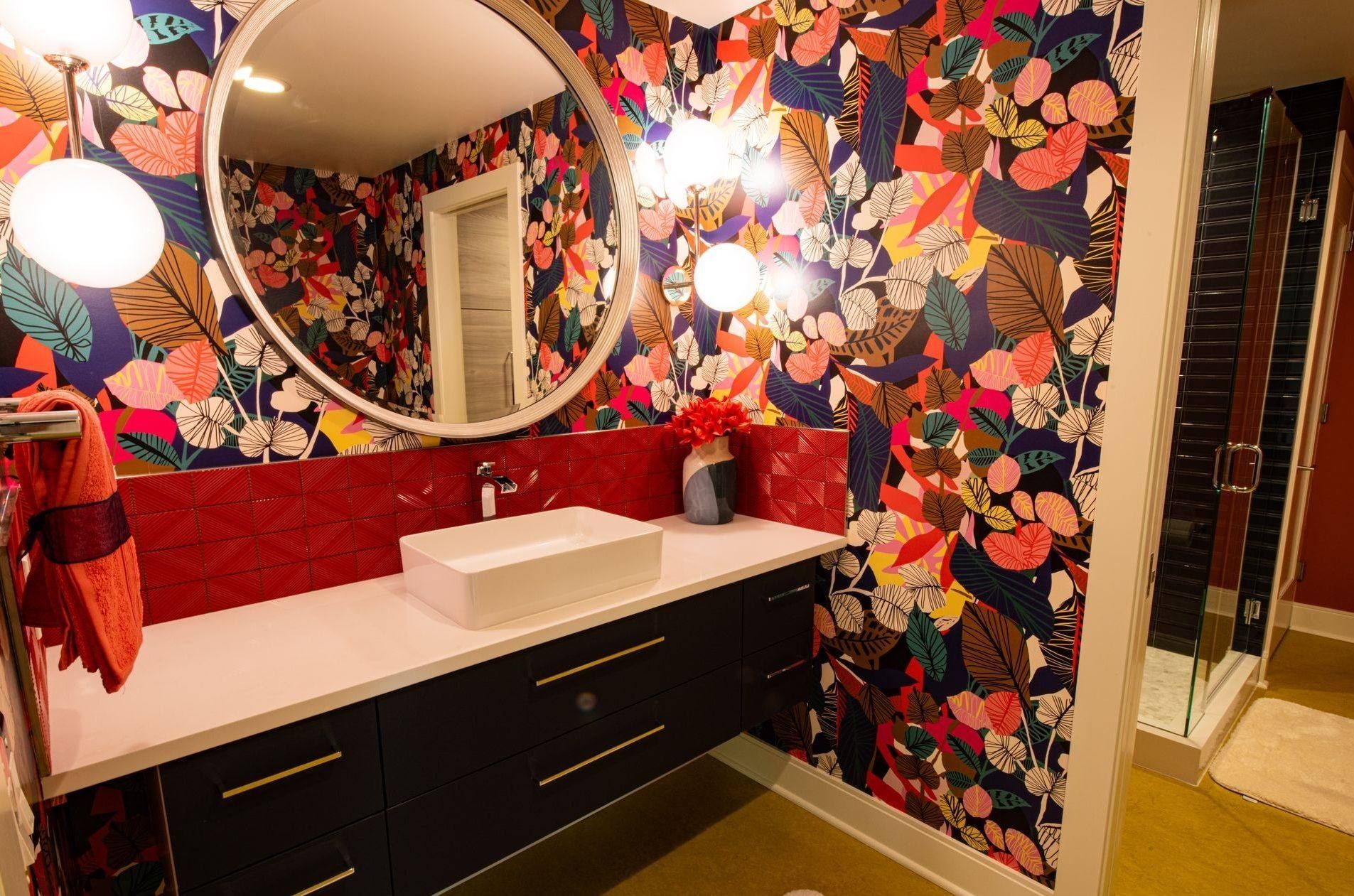 A bathroom with a sink , mirror and floral wallpaper.