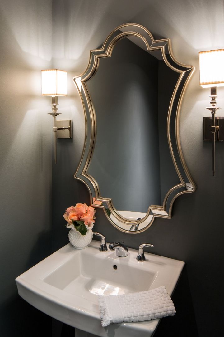 A bathroom sink with a mirror above it and a vase of flowers.