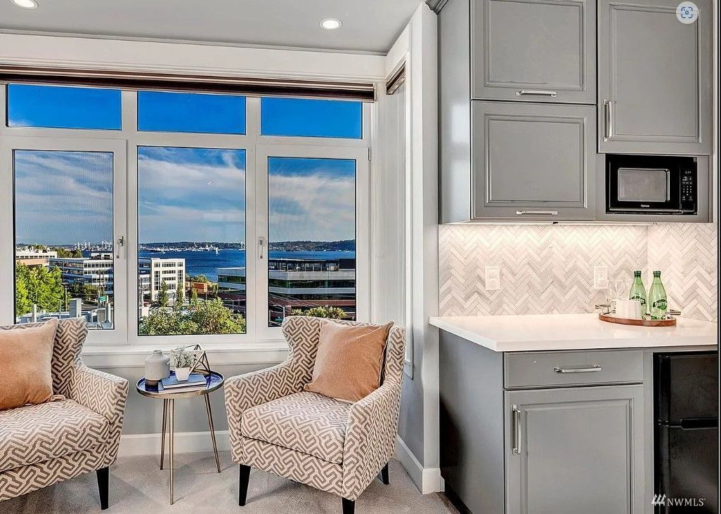 A living room with two chairs and a window with a view of the ocean.
