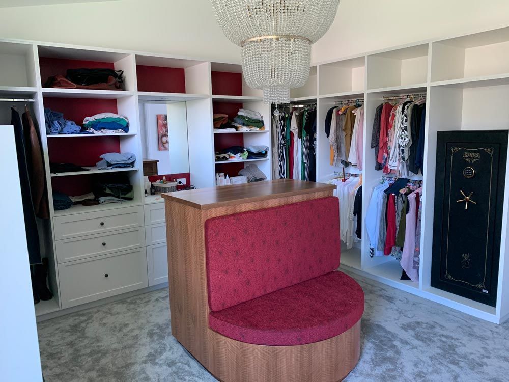 A Large Walk In Closet With Lots Of Clothes And A Red Bench — Ben Lynch Cabinetmaking in South Lismore, NSW