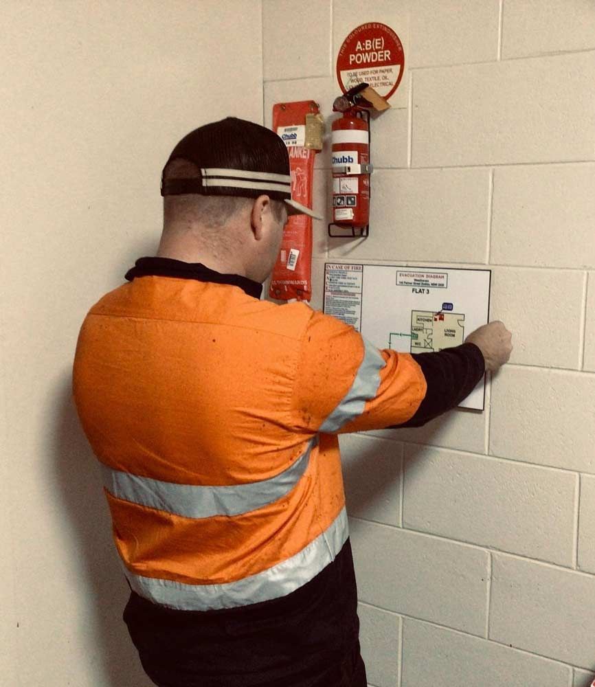 A Man In An Orange Safety Vest Is Looking At A Map On A Wall — Firewerx In Dubbo, NSW