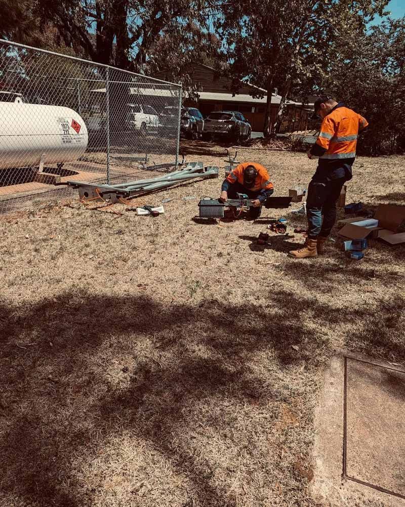 A Group Of Men Are Working On A Propane Tank In A Yard — Firewerx In Dubbo, NSW