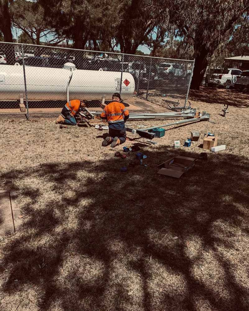Two Men Are Working On A Propane Tank In A Field — Firewerx In Orange, NSW