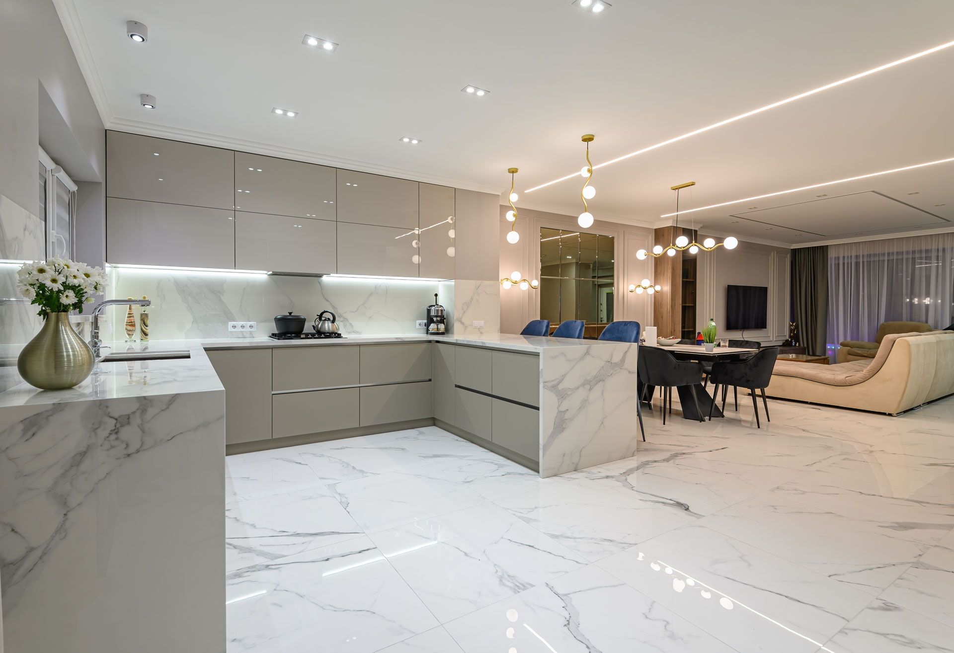 Modern kitchen with marble countertops, gray cabinets, and dining area with a table and chairs.