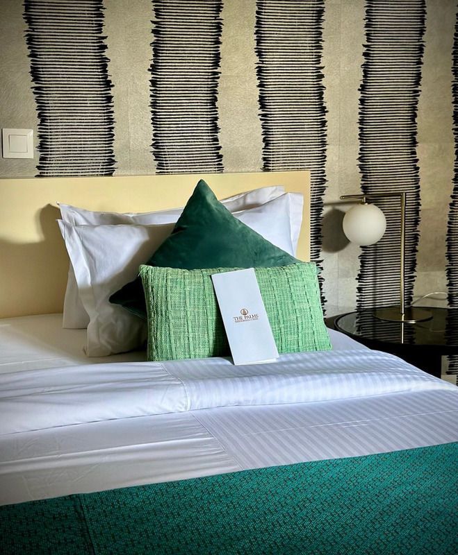 Un lit avec des draps blancs et des oreillers verts dans une chambre d'hôtel