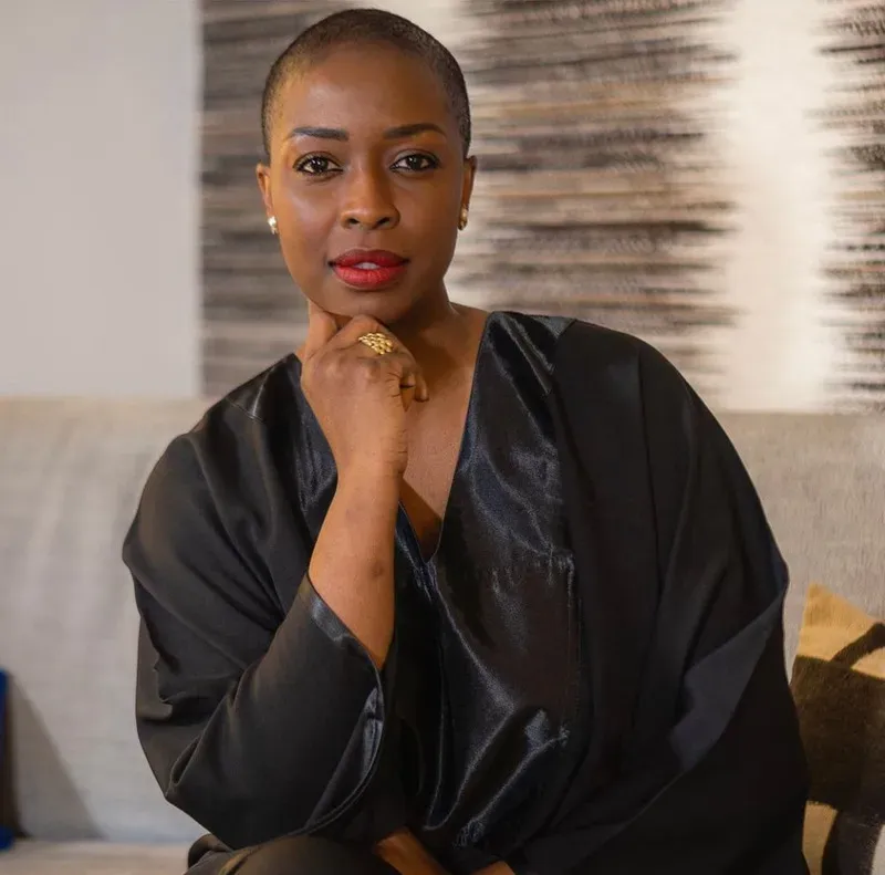 Une femme est assise sur un canapé avec sa main sur son menton