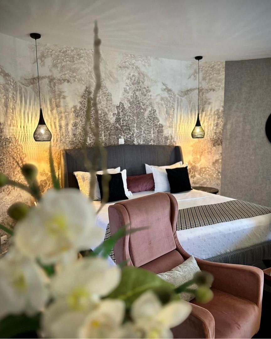 Une chambre d'hôtel avec un lit, une chaise et des fleurs au premier plan.