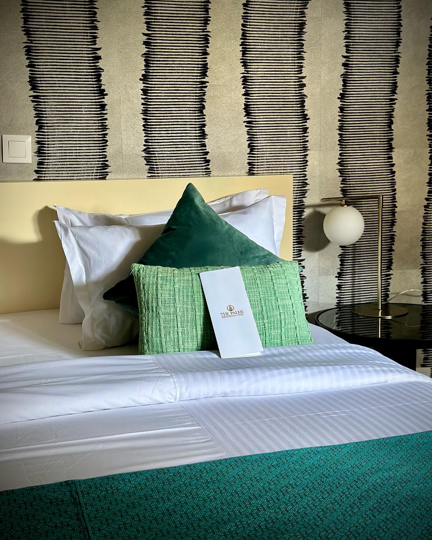 Un lit avec des draps blancs et des oreillers verts dans une chambre d'hôtel.