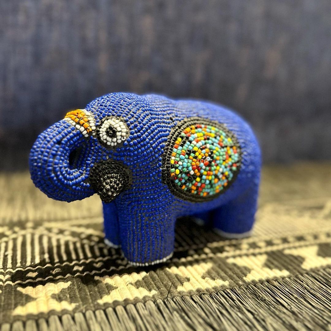 Un éléphant en peluche bleu est assis sur un tapis.