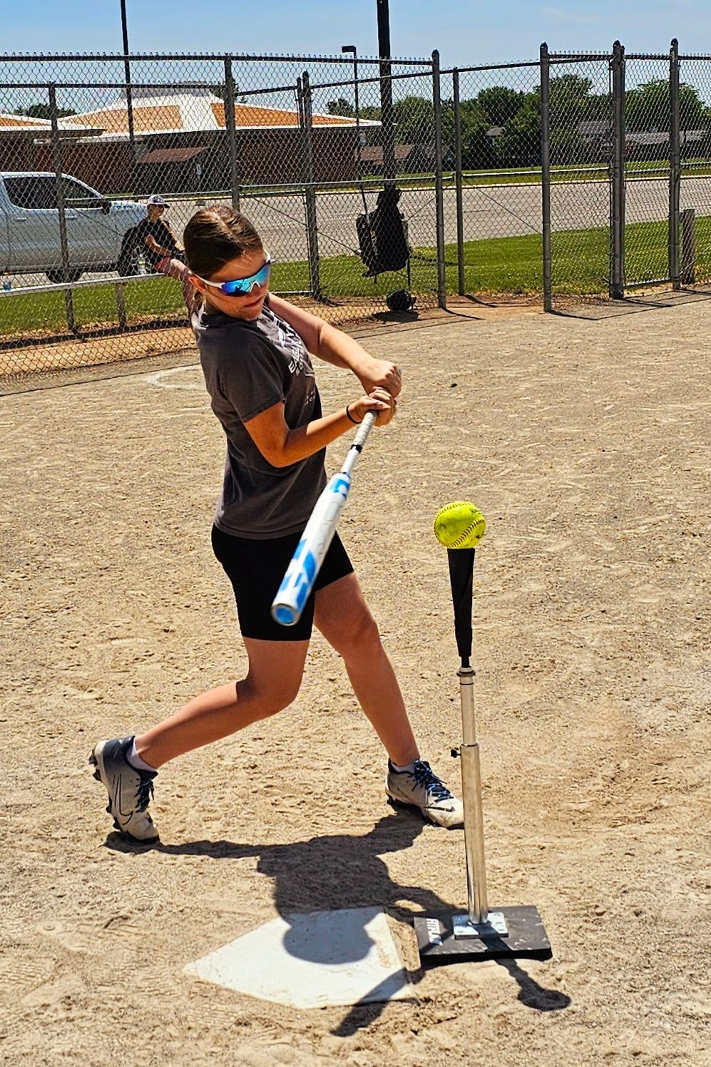 A young girl is swinging a bat at a baseball on a tee.