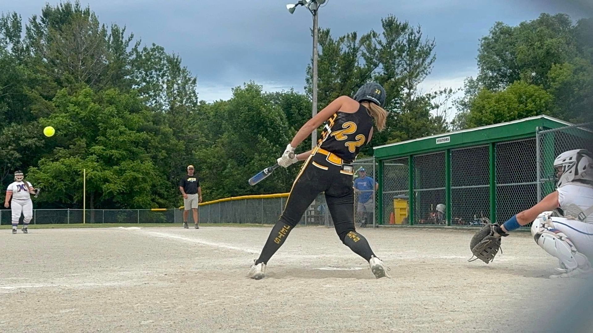 A woman is swinging a bat at a ball on a baseball field. Softball and baseball training