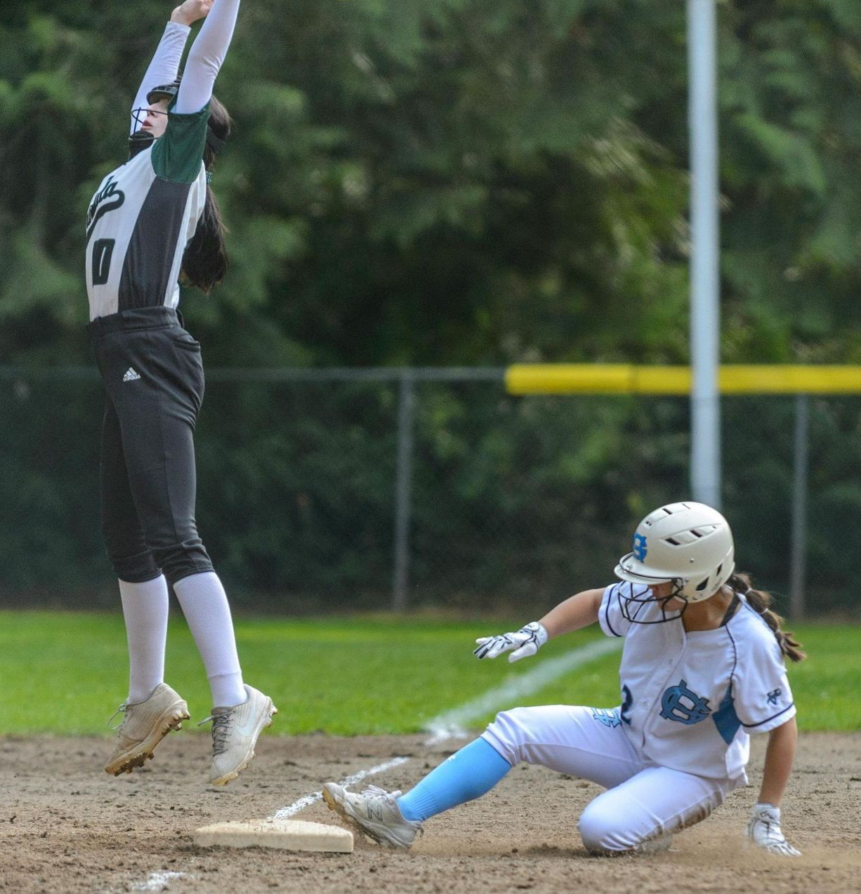 A girl is sliding into second base during a softball game. Softball and baseball training
