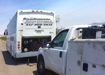 A white truck is parked next to a white bus.