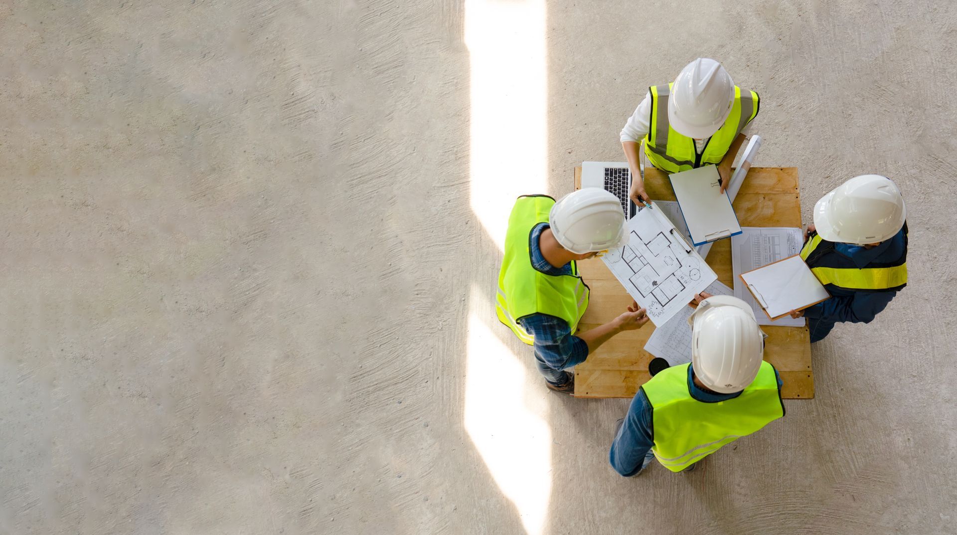 A group of construction workers are sitting around a table looking at a blueprint.
