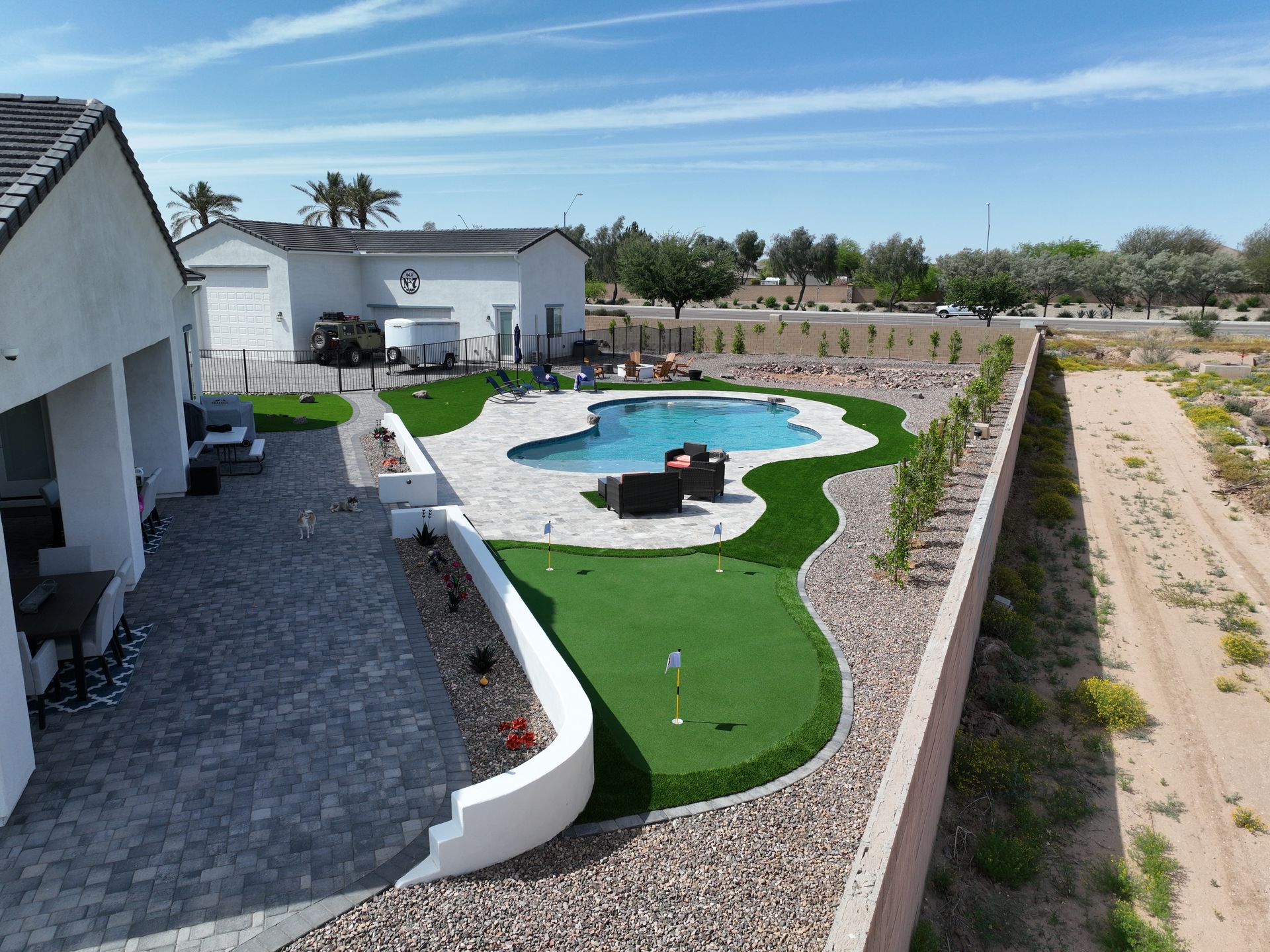 An aerial view of a backyard with a pool and a putting green