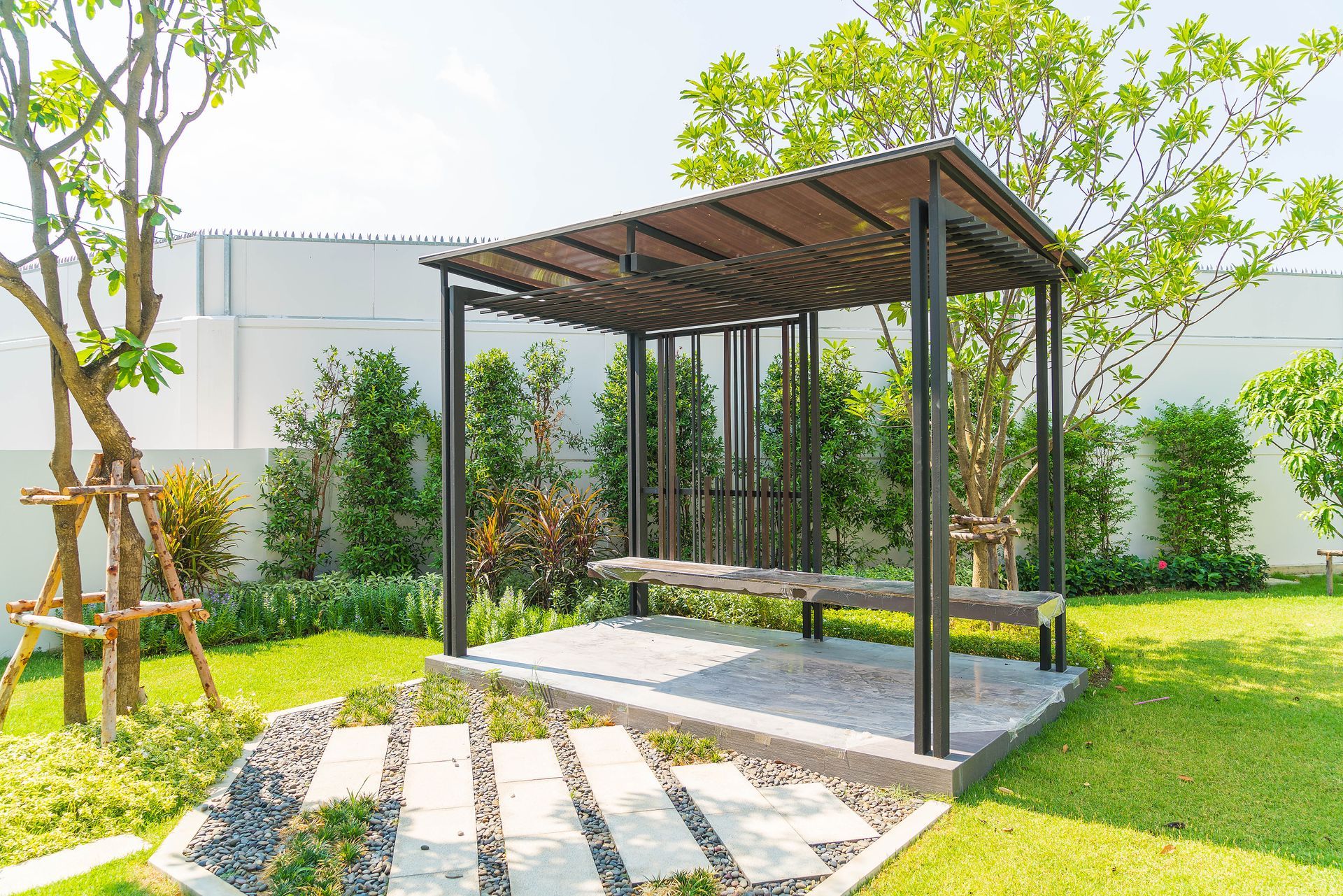 A pergola with a bench in the middle of a garden.
