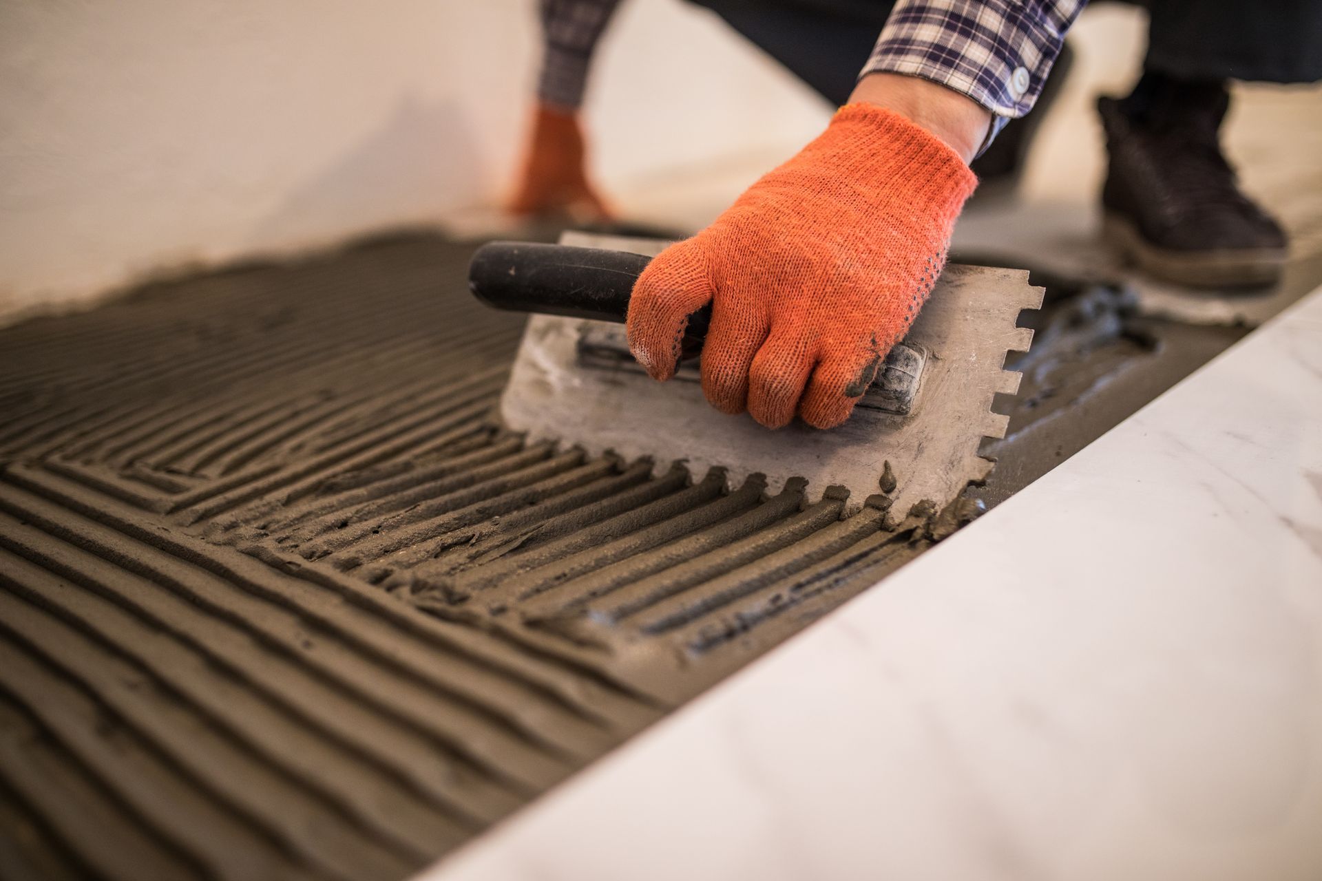 A person is laying tile on the floor with a trowel.