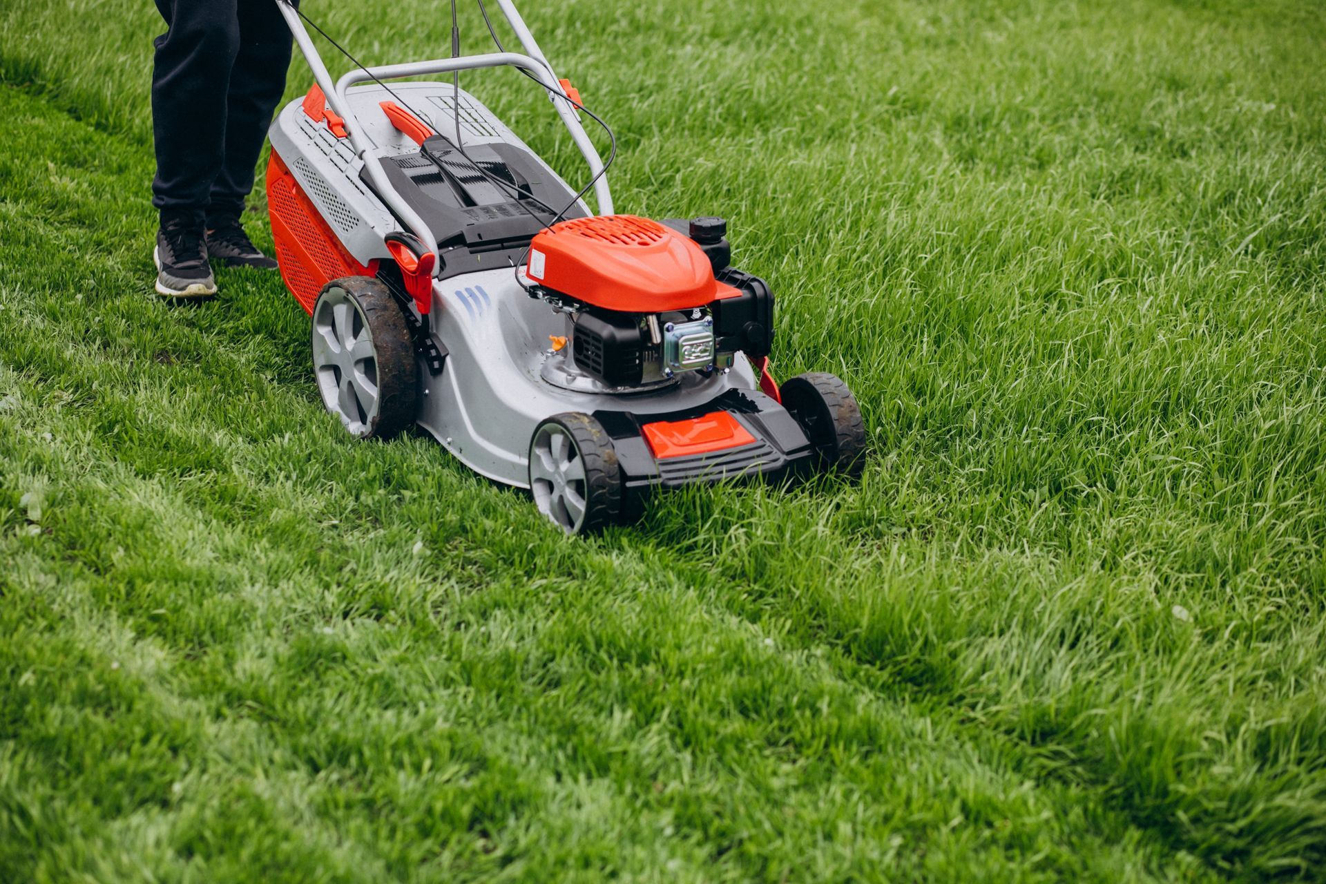 A man is mowing a lush green lawn with a lawn mower.