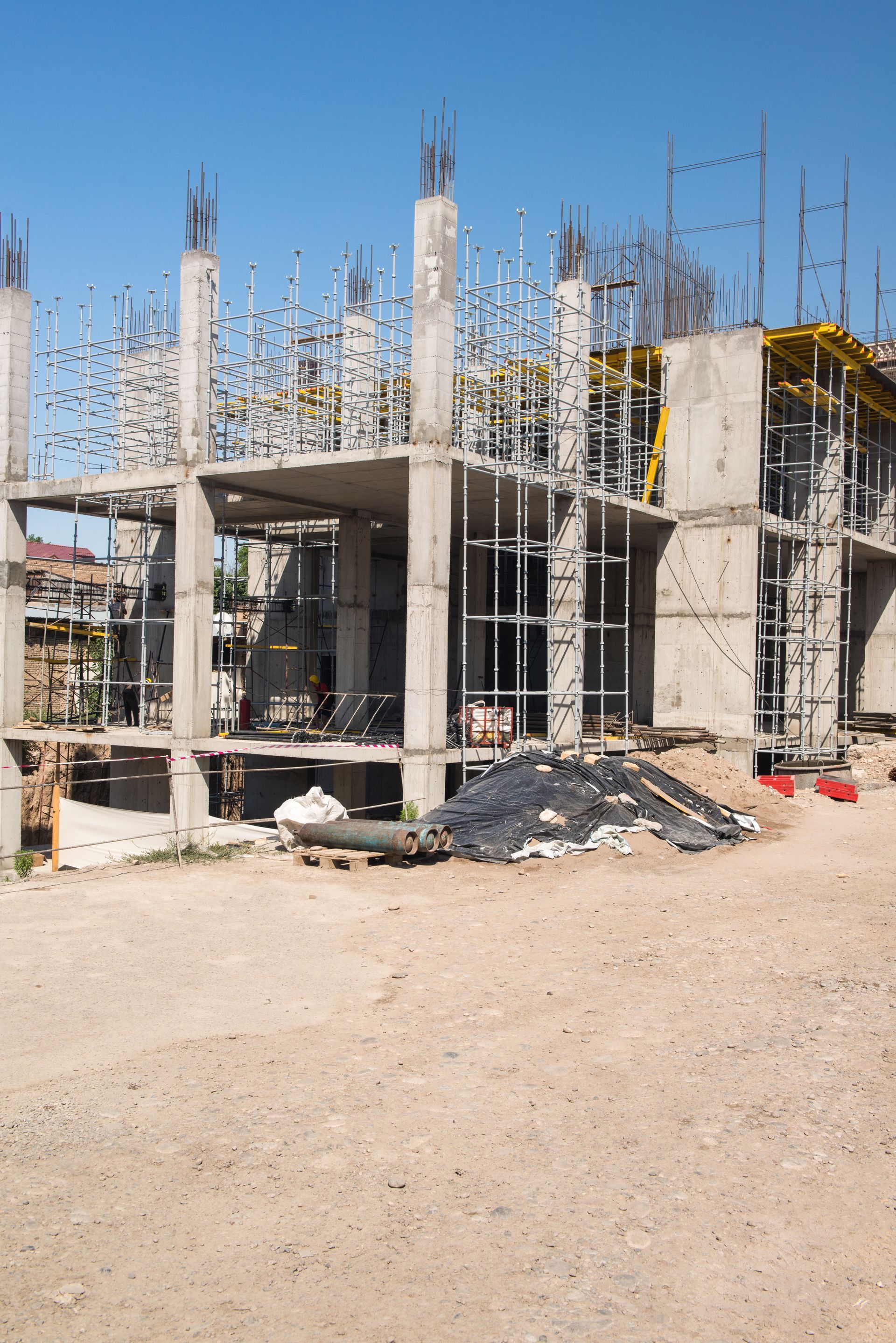 A large building is being built on a dirt field.