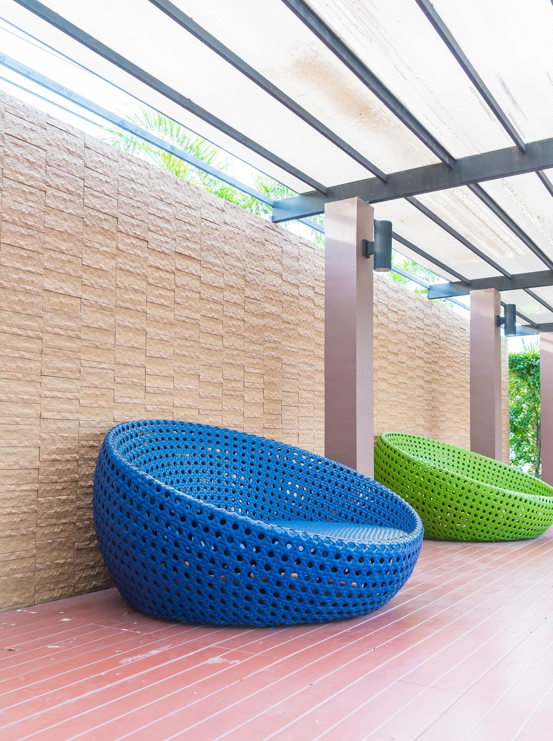 A blue chair and a green chair are sitting on a wooden deck.