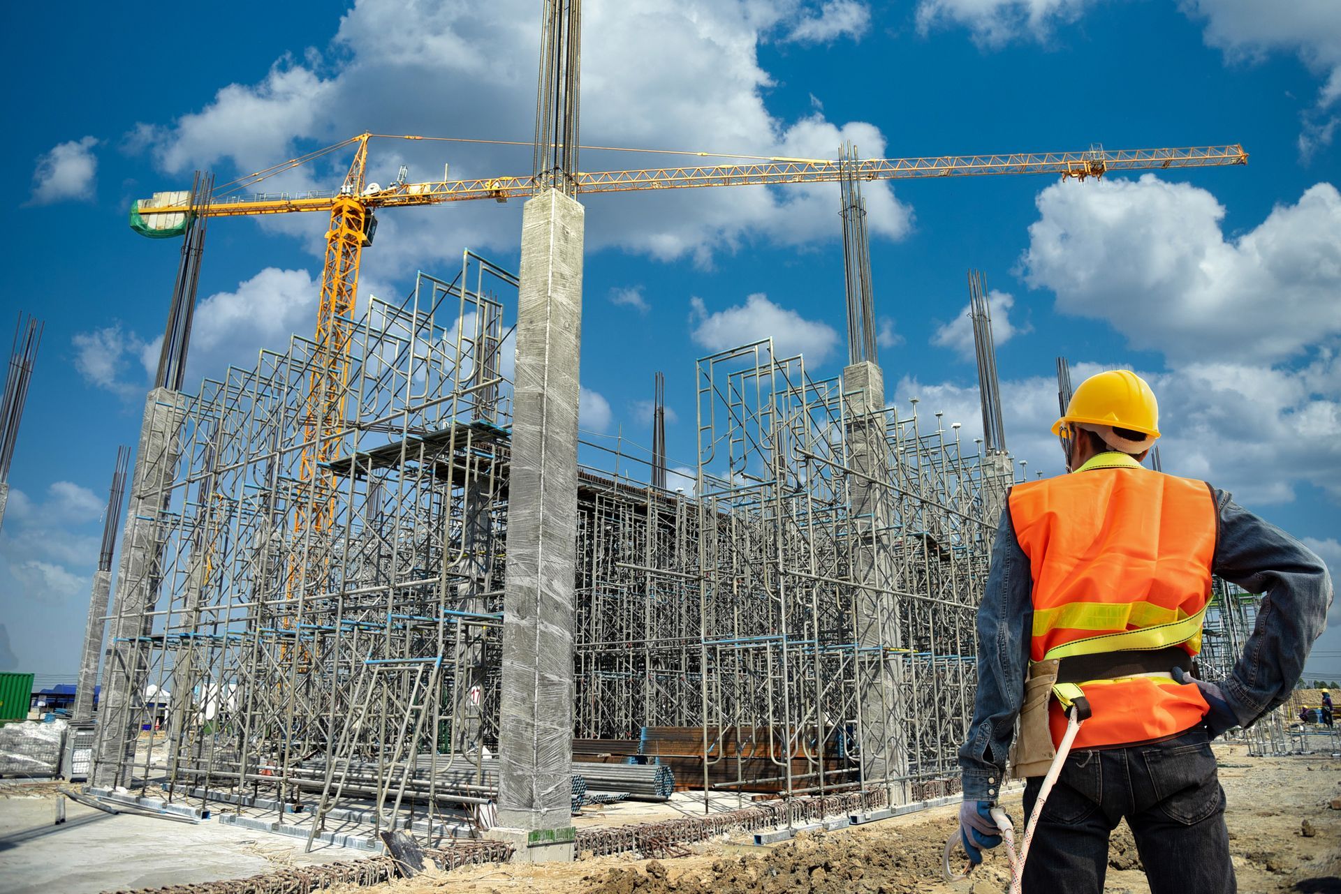 A construction worker is standing in front of a building under construction.