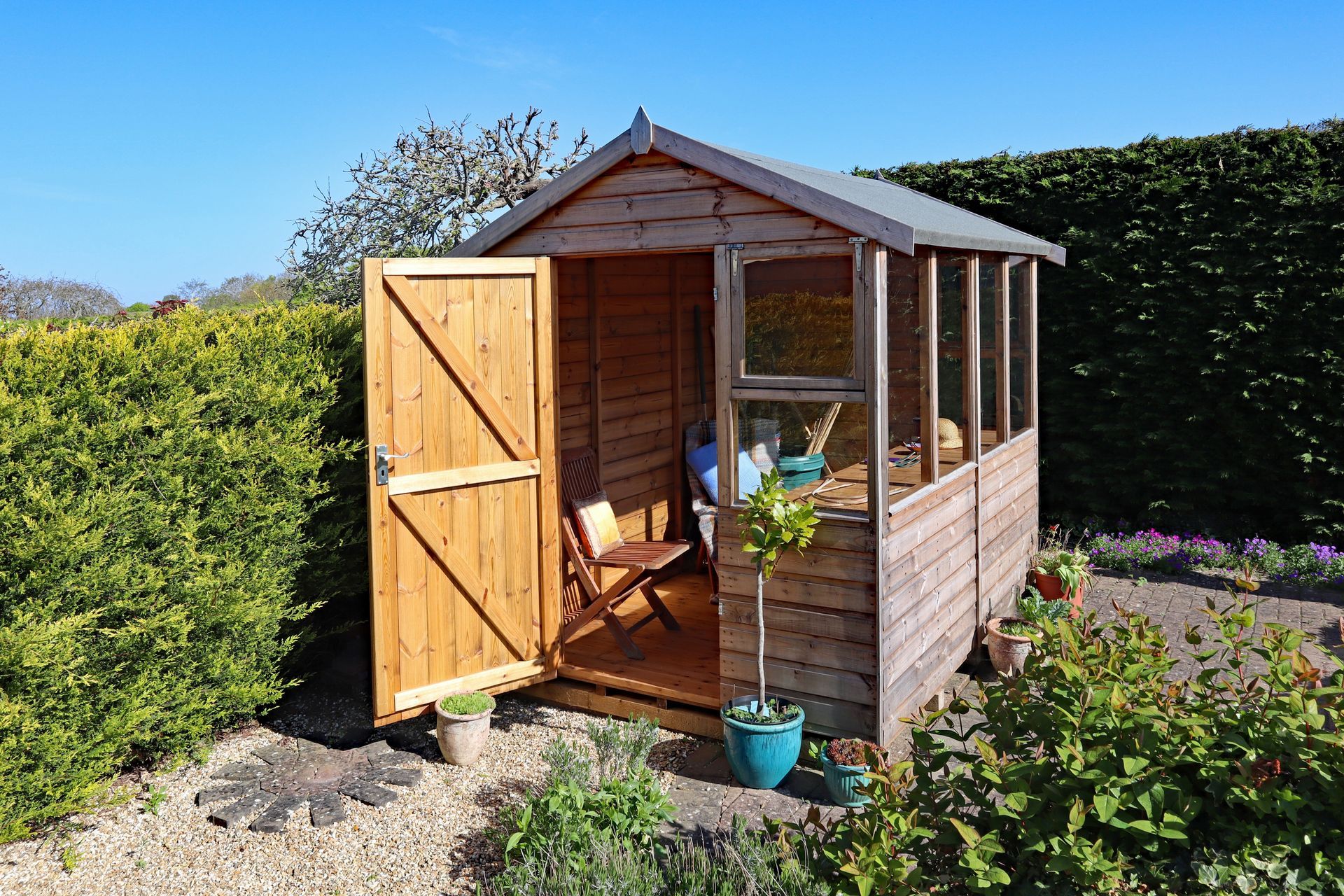A wooden shed with the door open in a garden
