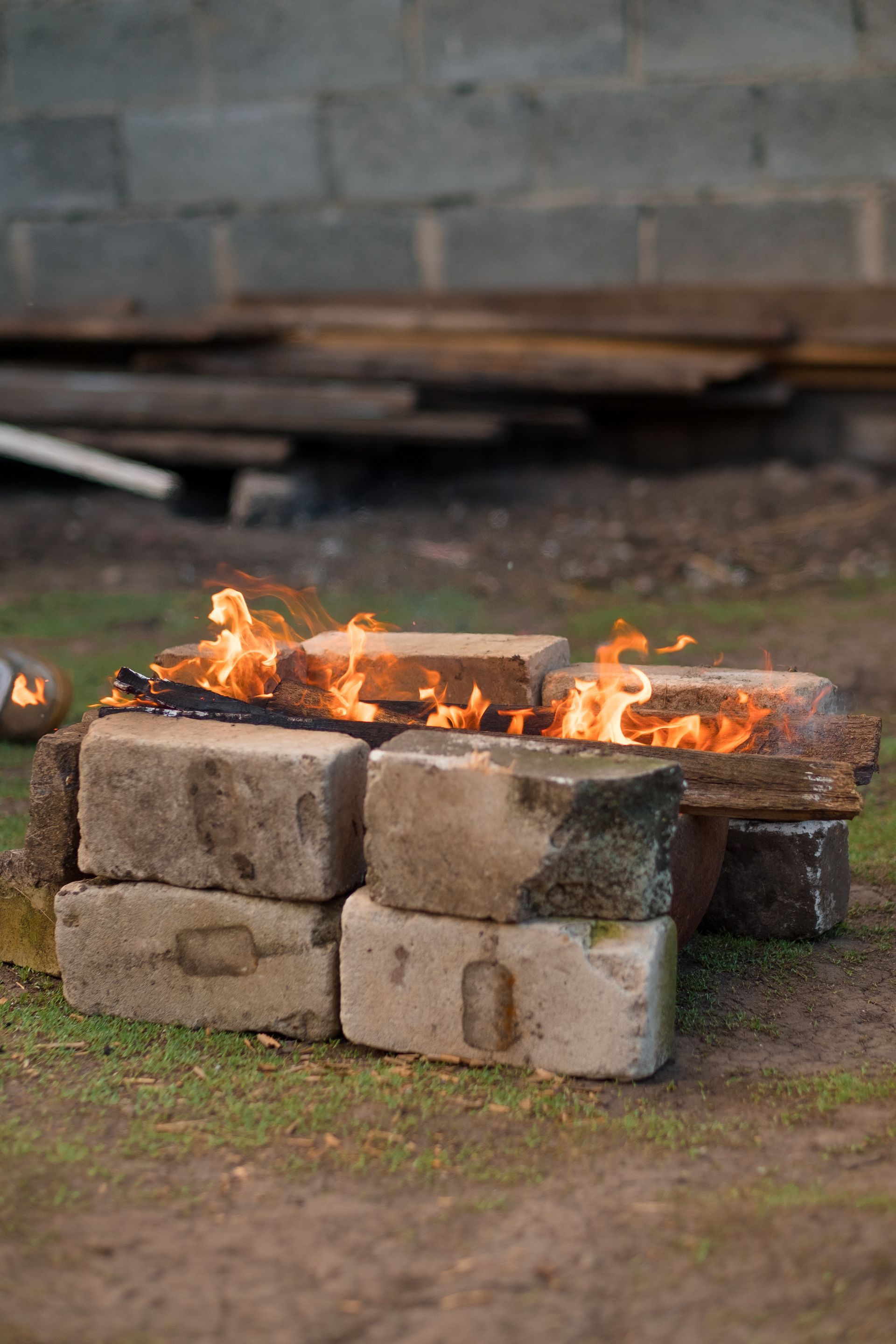 A fire pit made out of bricks in the grass.