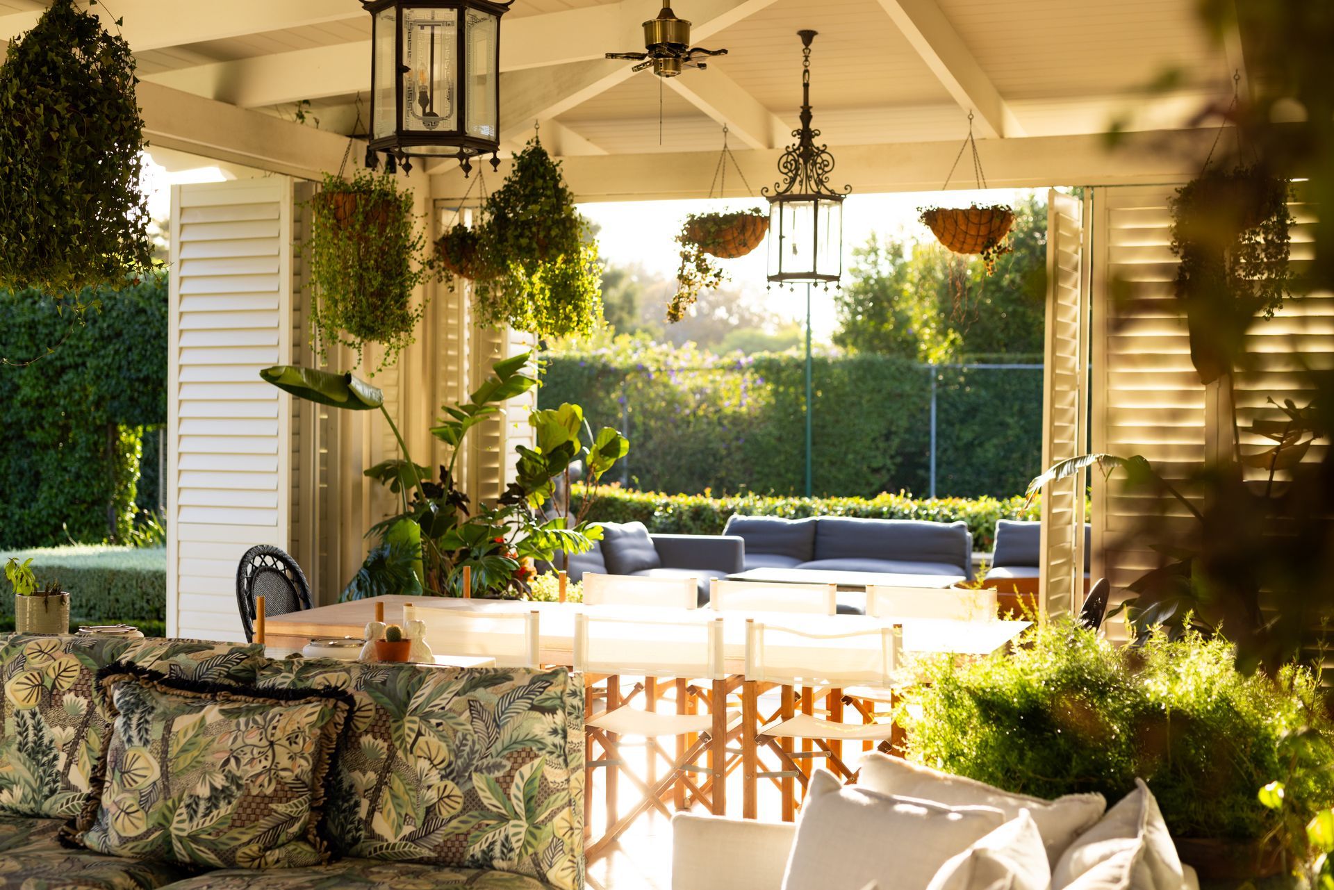 A patio with a couch and a table with lanterns hanging from the ceiling