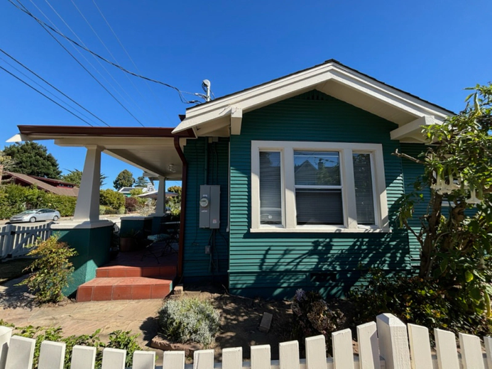 A small green house with a white picket fence in front of it