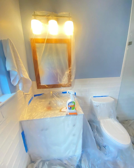 A bathroom with a sink , toilet and mirror covered in plastic.