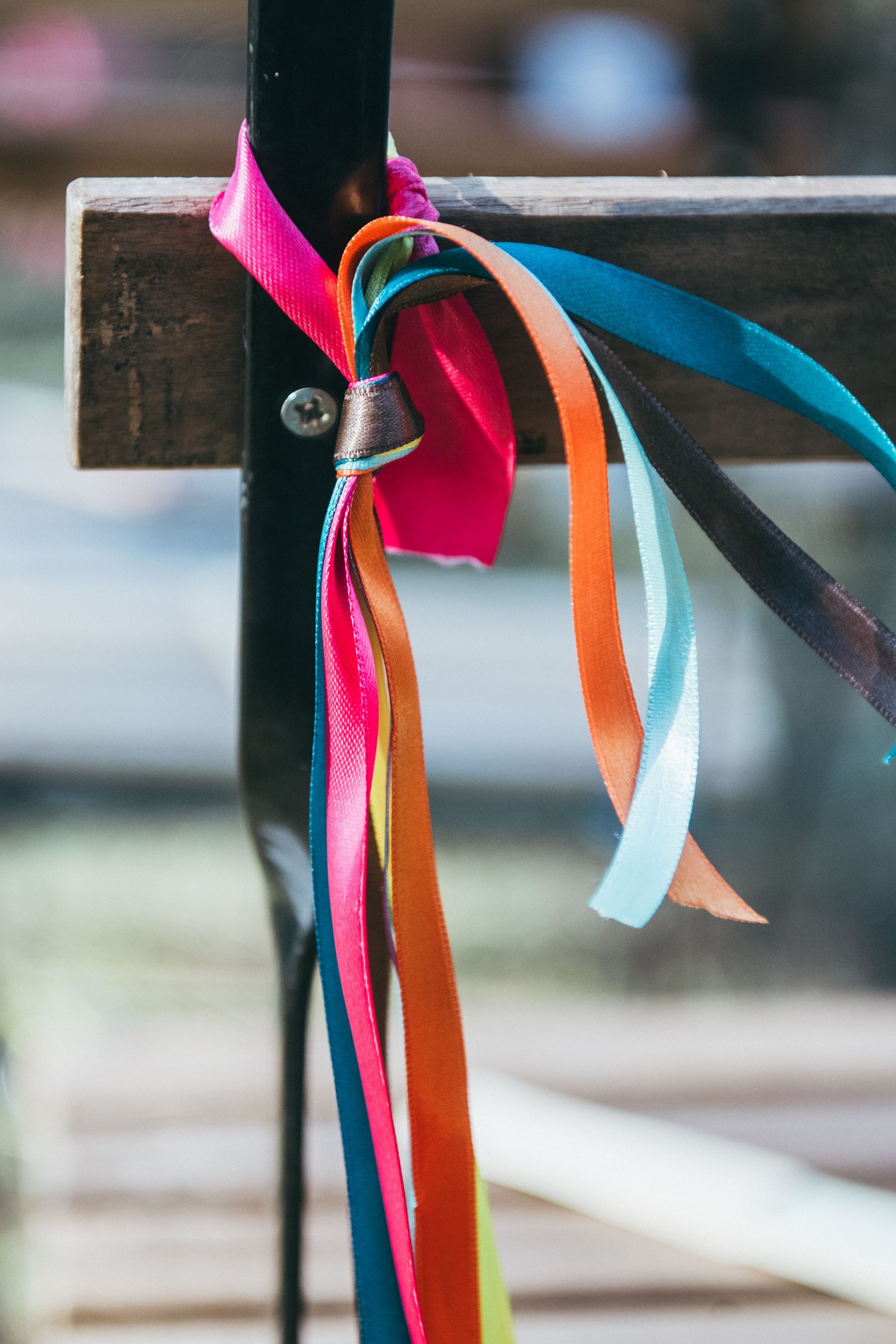 Nastri luminosi legati a un palo di metallo scuro e a una trave di legno, probabilmente all'aperto.