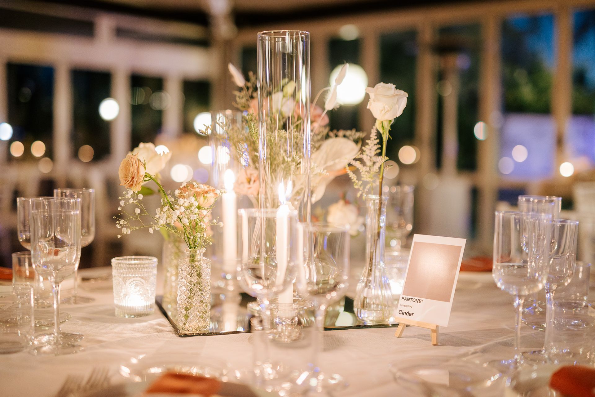Elegante centrotavola per matrimonio: fiori, candele, bicchieri da champagne e una piccola cornice.