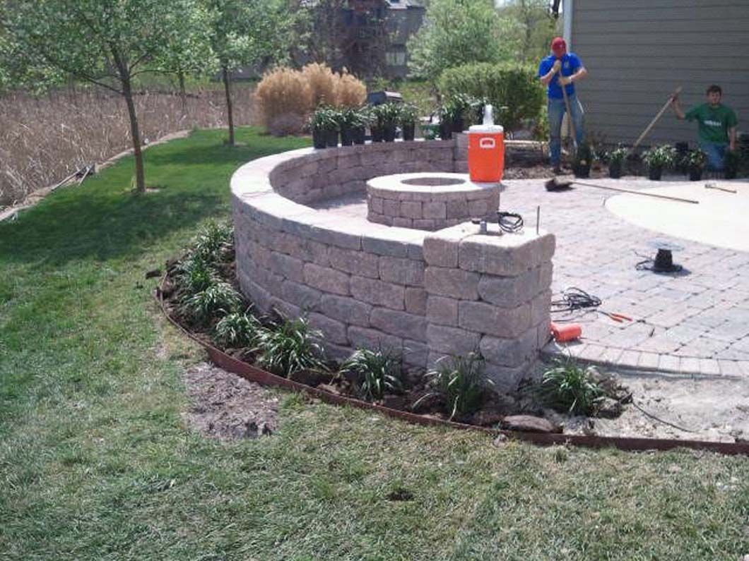 A man is standing next to a fire pit in a backyard.