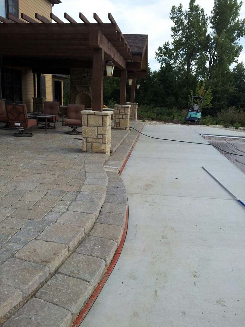 A patio with a pergola and chairs in front of a house.