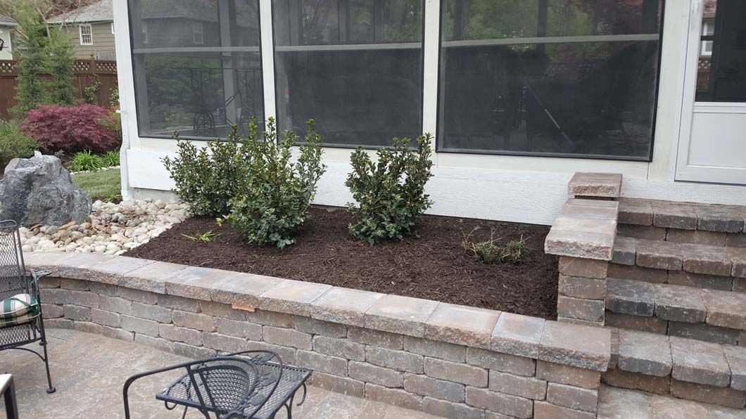 A patio with a screened in porch and a brick wall.
