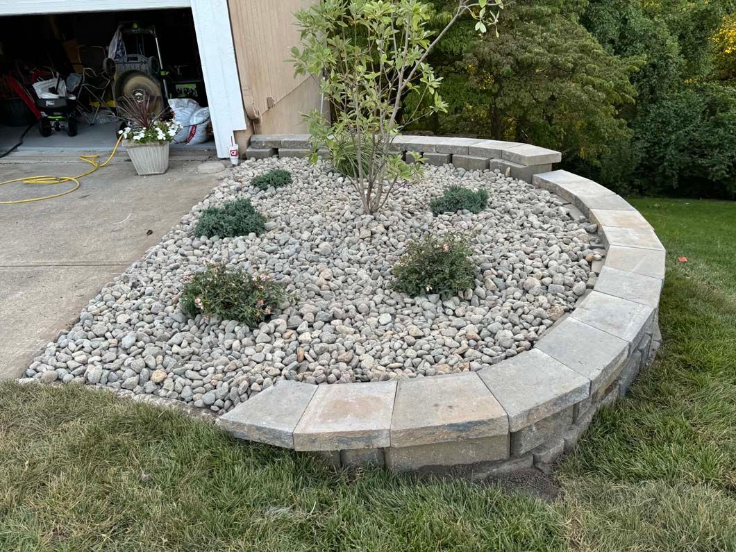 A garden with rocks and plants in front of a garage.