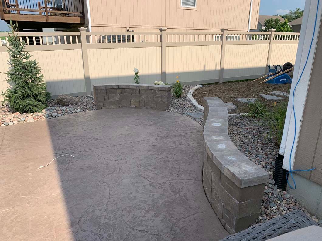 A patio with a brick wall and a fence in front of a house.