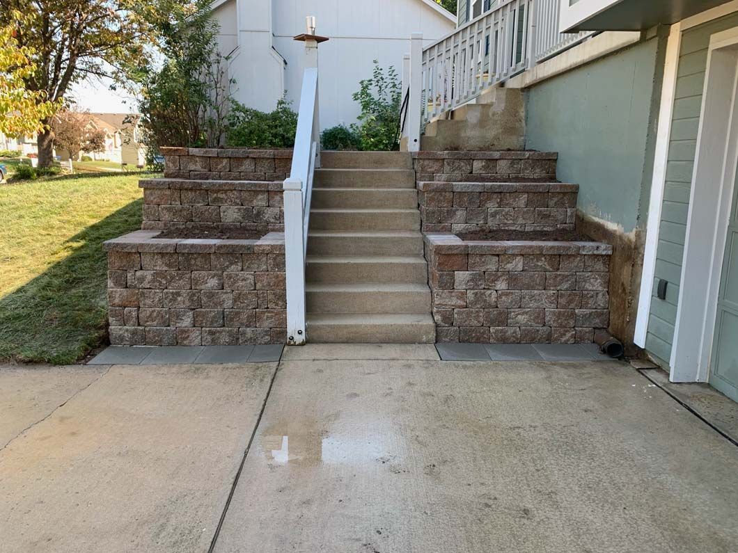 A set of stairs leading up to a house with a stone wall.