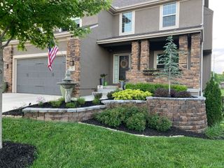 A large house with a large lawn and a brick wall in front of it.