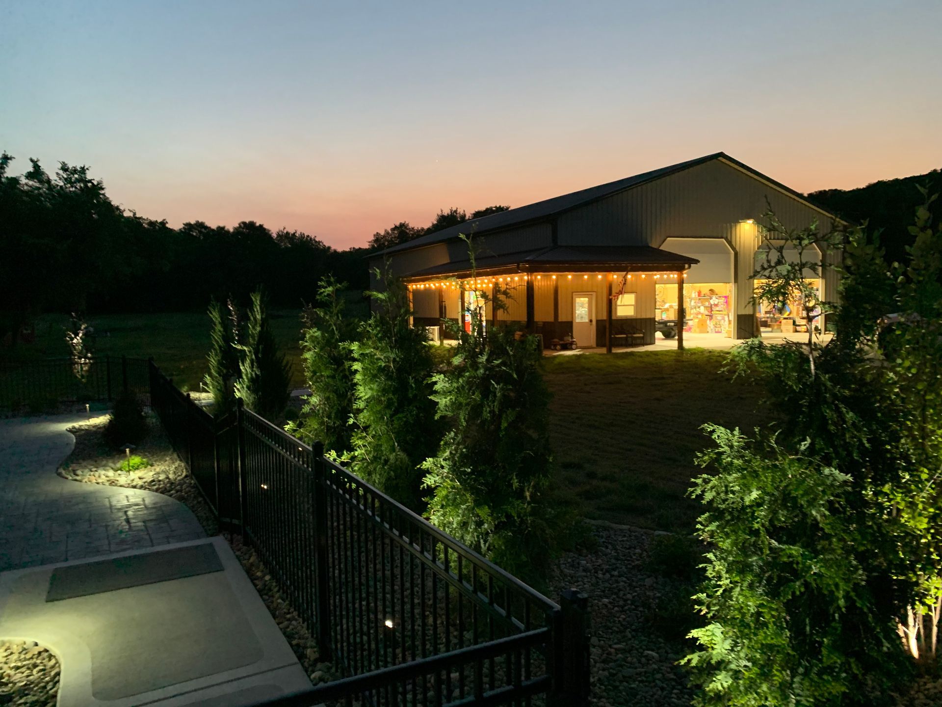 A large house is lit up at night with a fence in front of it.