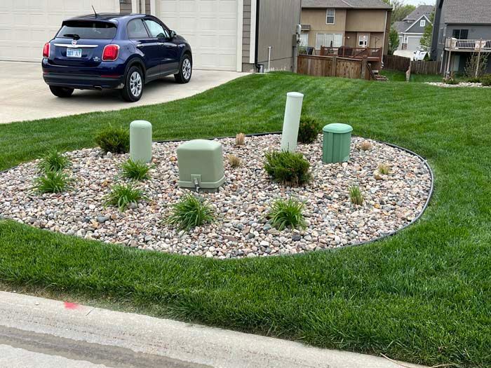 A blue car is parked in front of a lush green lawn.