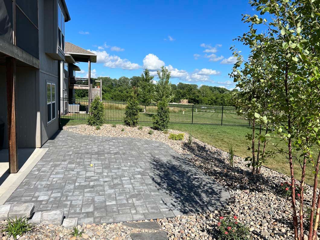 A brick driveway leading to a house with a screened in porch.