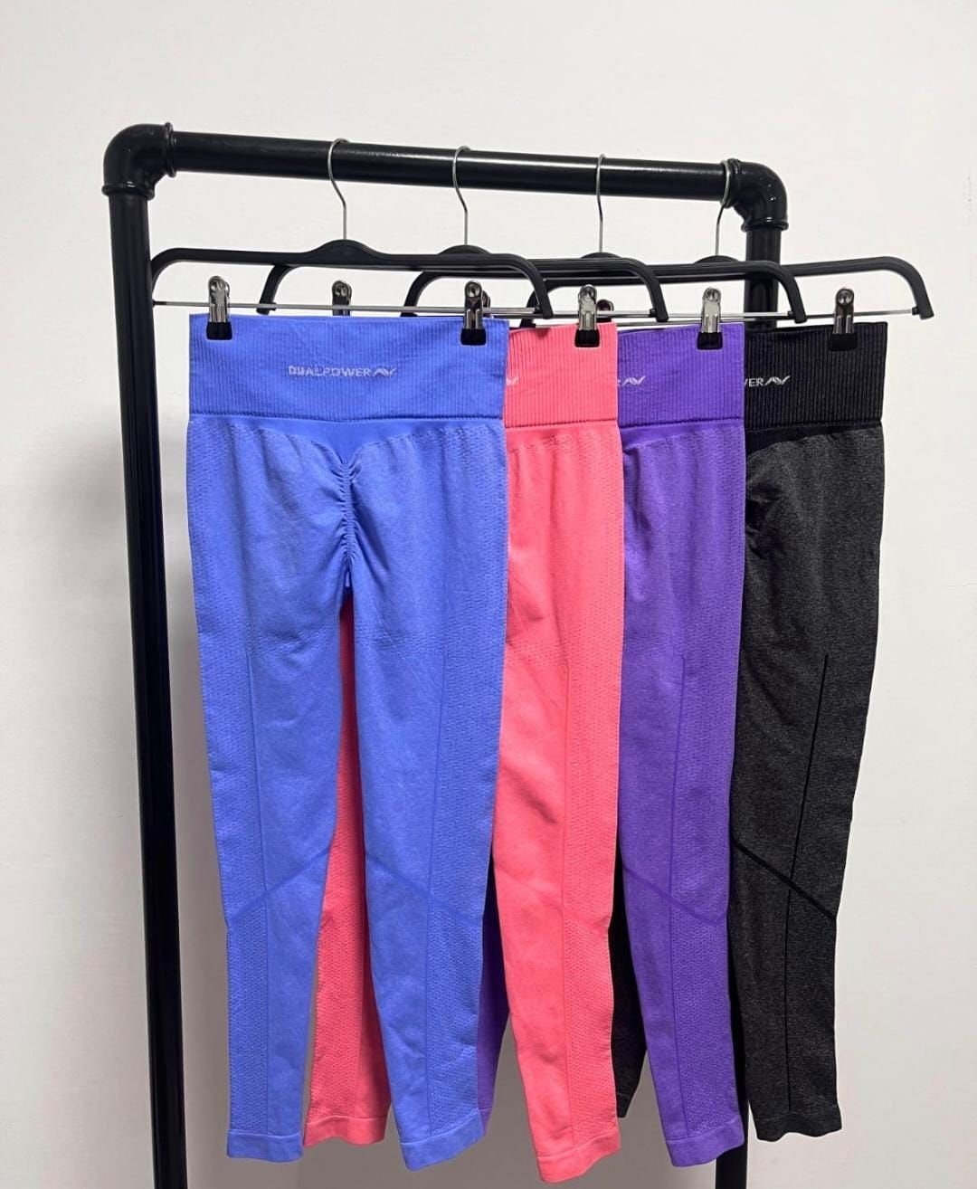 Tres pares de mallas deportivas: azules, violetas y rosas, cada una con una etiqueta amarilla.