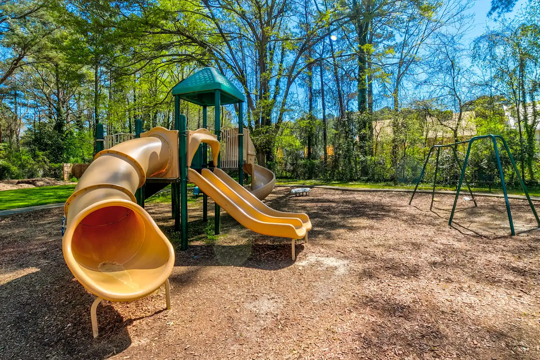 A playground with a slide and swings in a park.