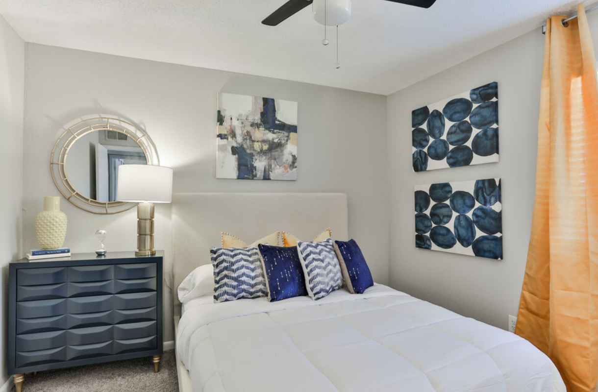 A bedroom with a bed , dresser , mirror and ceiling fan.