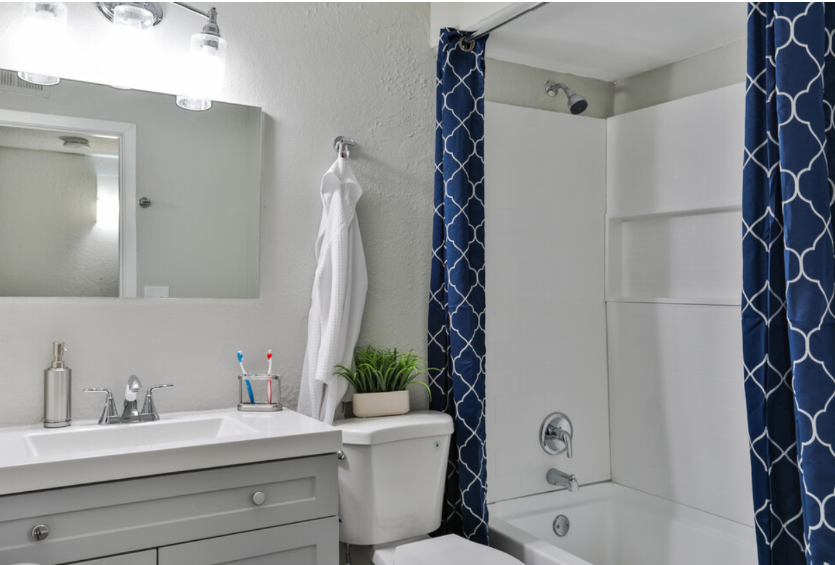A bathroom with a sink , toilet , shower and blue shower curtain.