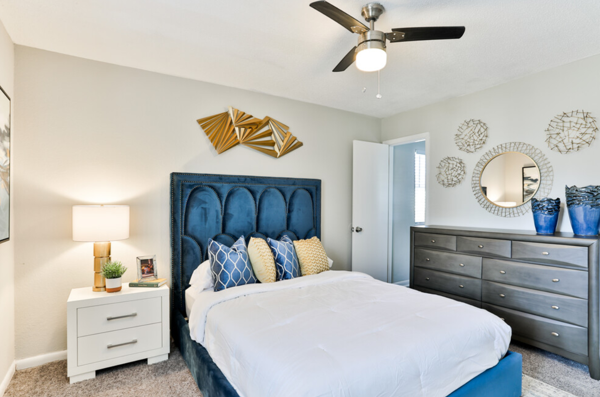 A bedroom with a bed , dresser , nightstand and ceiling fan.