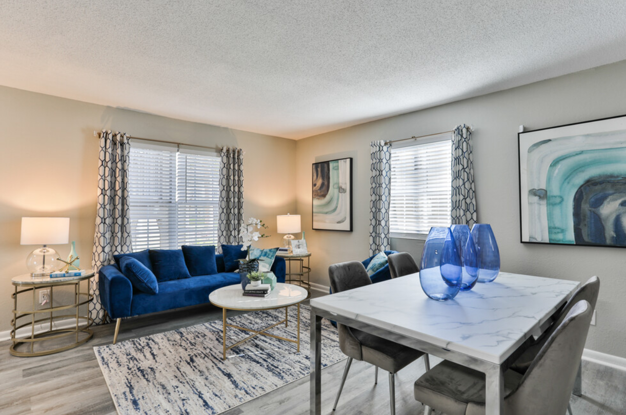 A living room with a blue couch , table and chairs.
