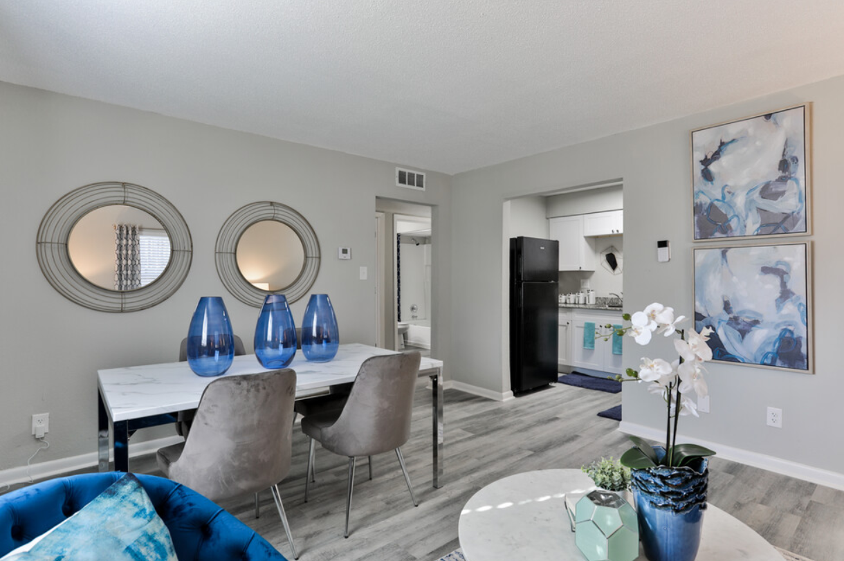 A living room with a dining table and chairs and a blue couch.