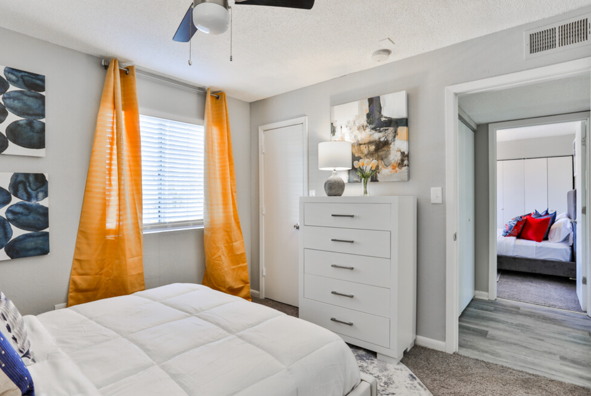 A bedroom with a bed , dresser , and ceiling fan.